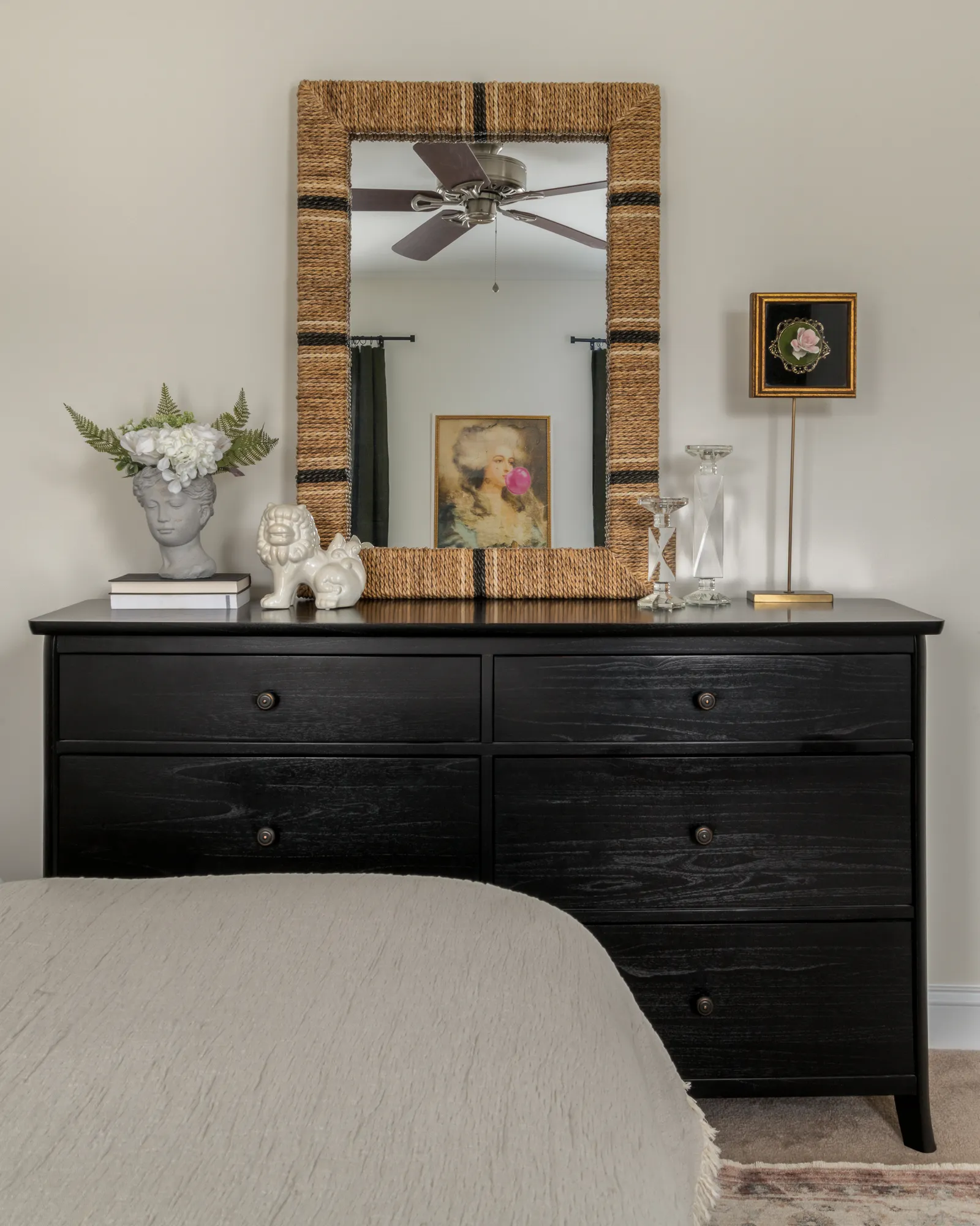 Black dresser with woven mirror and collected objects