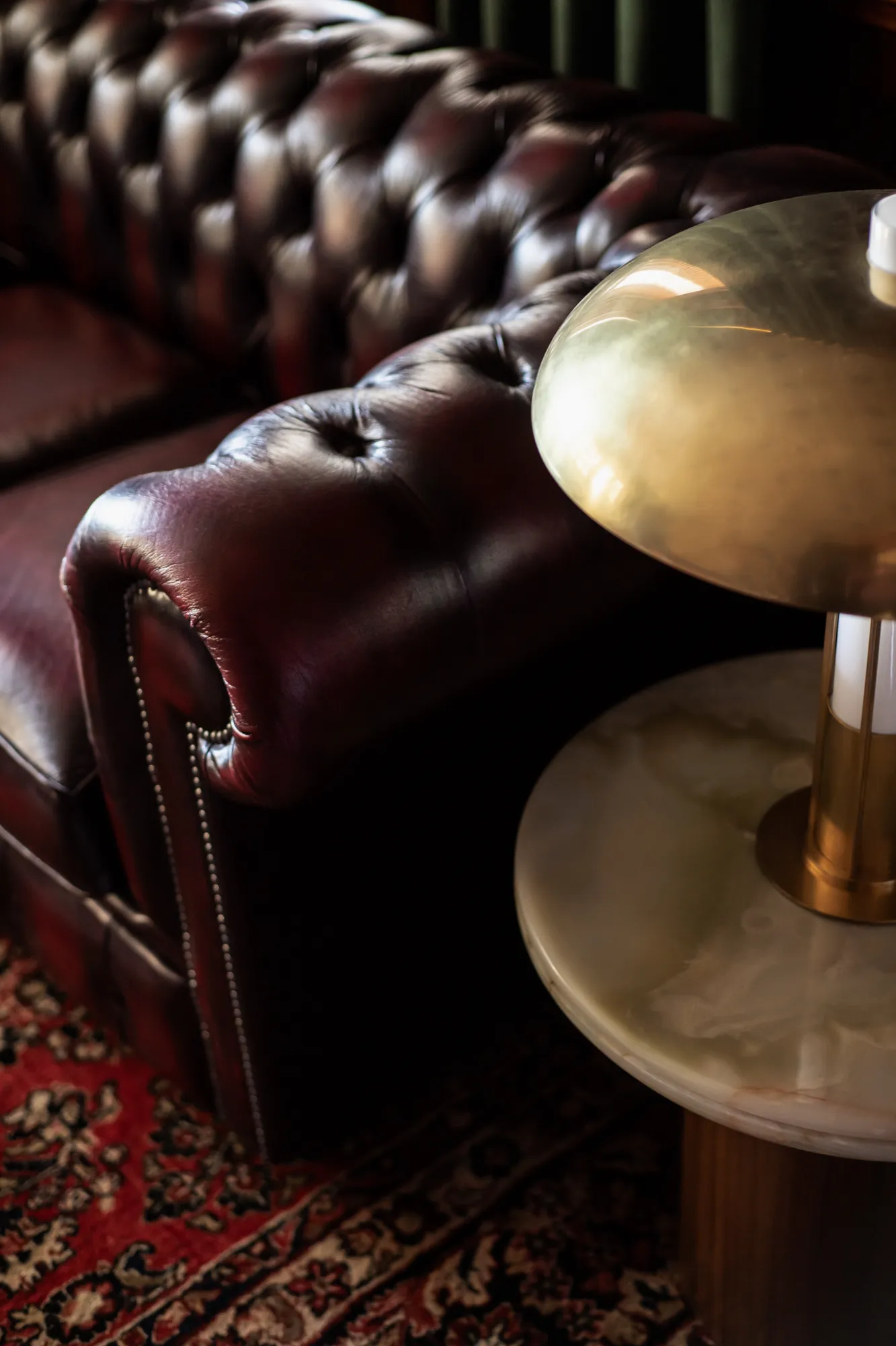 Tufted Chesterfield leather and brass mushroom lamp on marble side table