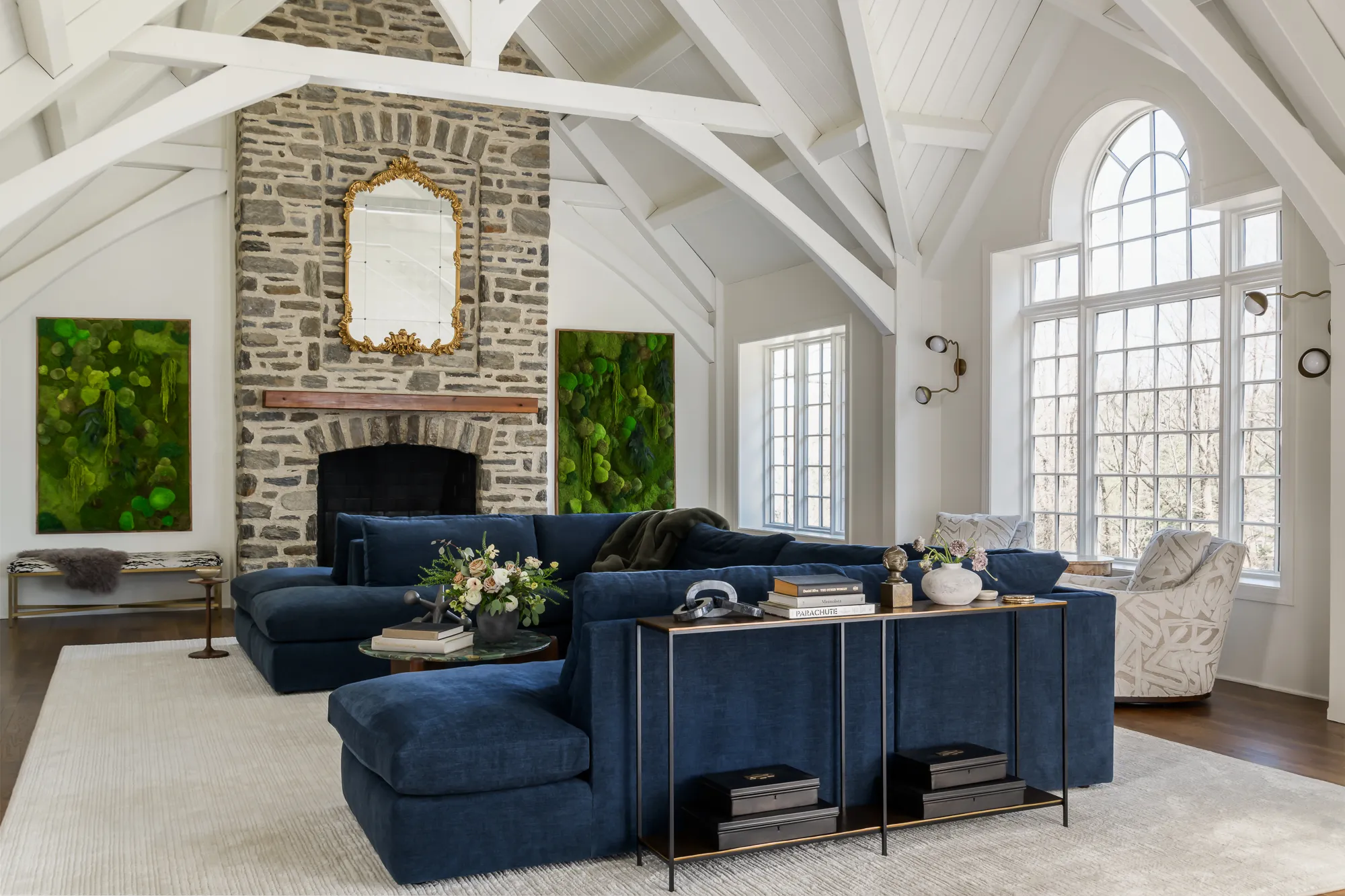 Vaulted great room with fieldstone fireplace, exposed beams, and navy sectional