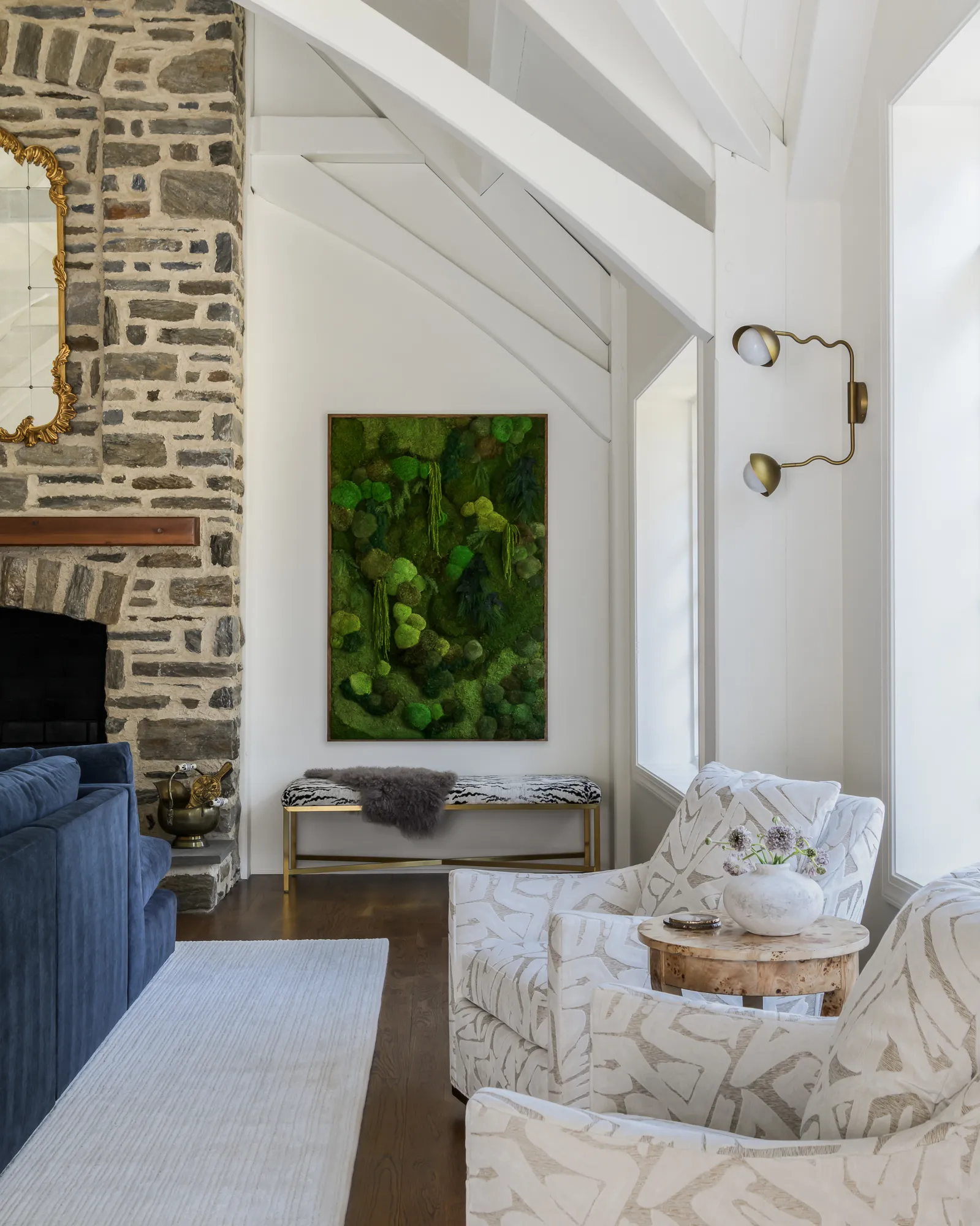 Great room seating area with moss wall art, patterned chairs, and fieldstone fireplace