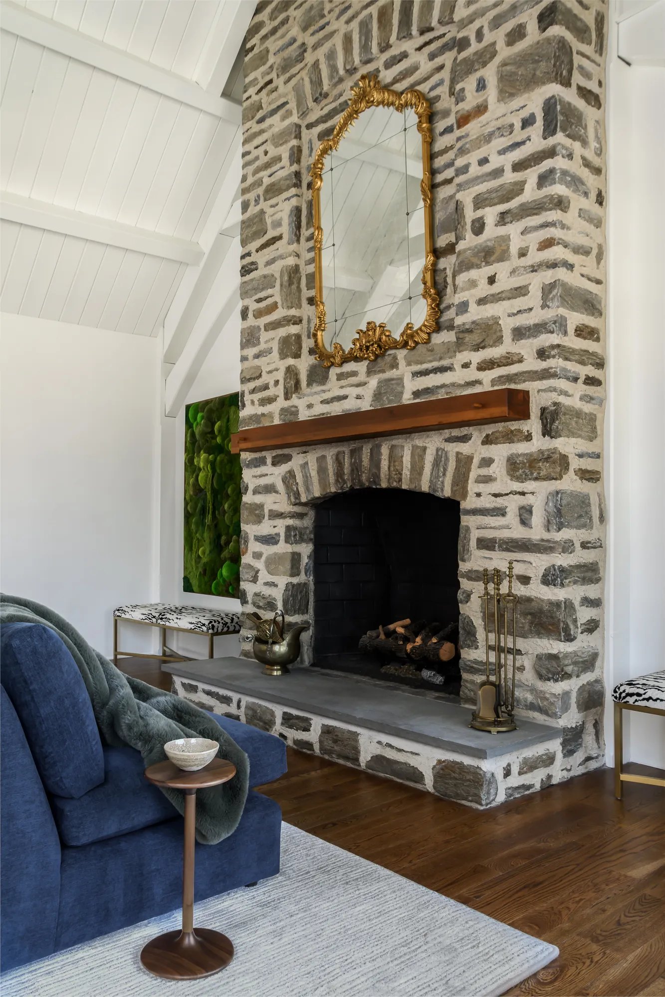 Stone fireplace detail with gold mirror and wood mantel