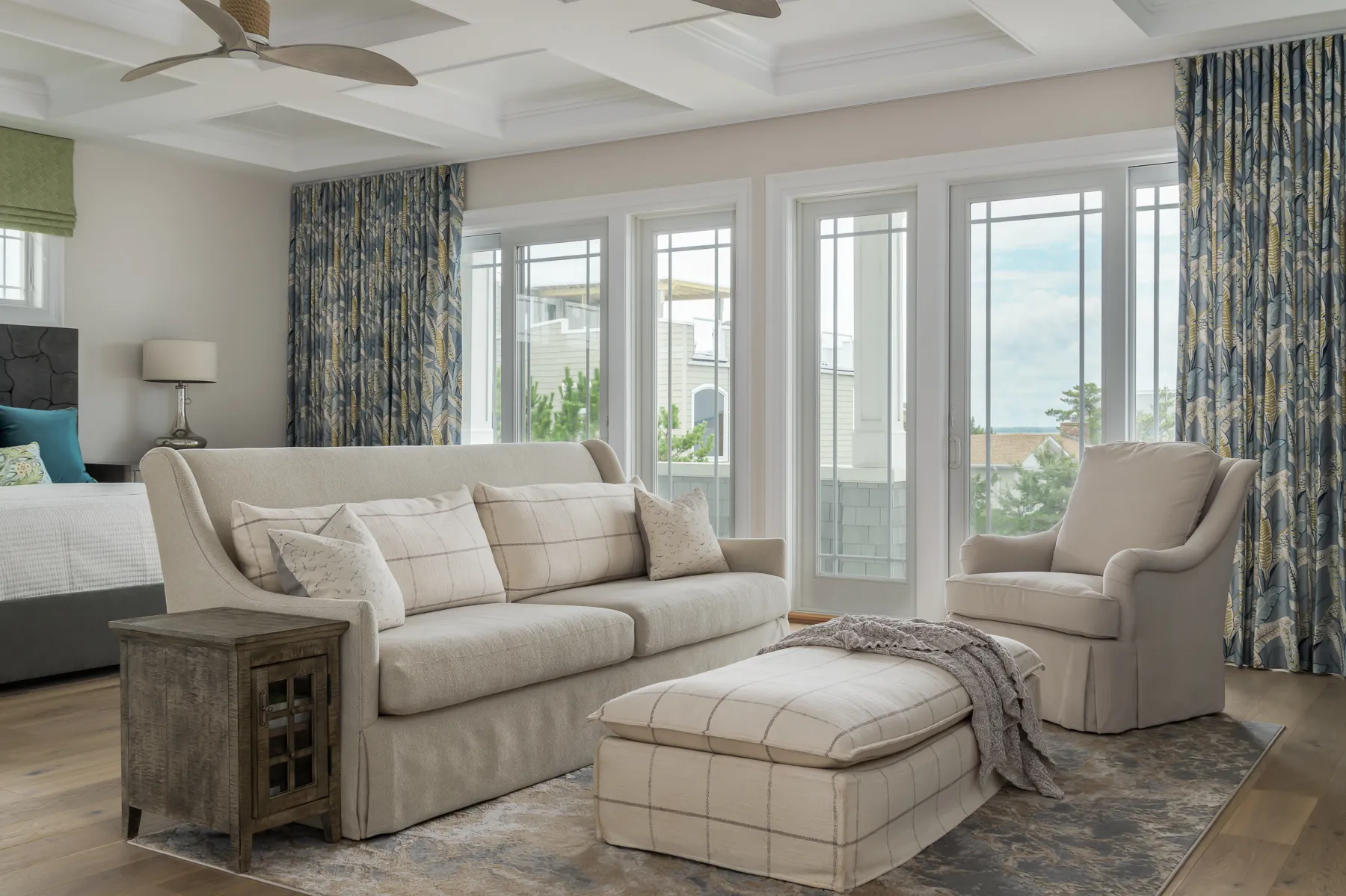 Primary sitting area with coffered ceiling, linen plaid sofa, and leaf-print curtains