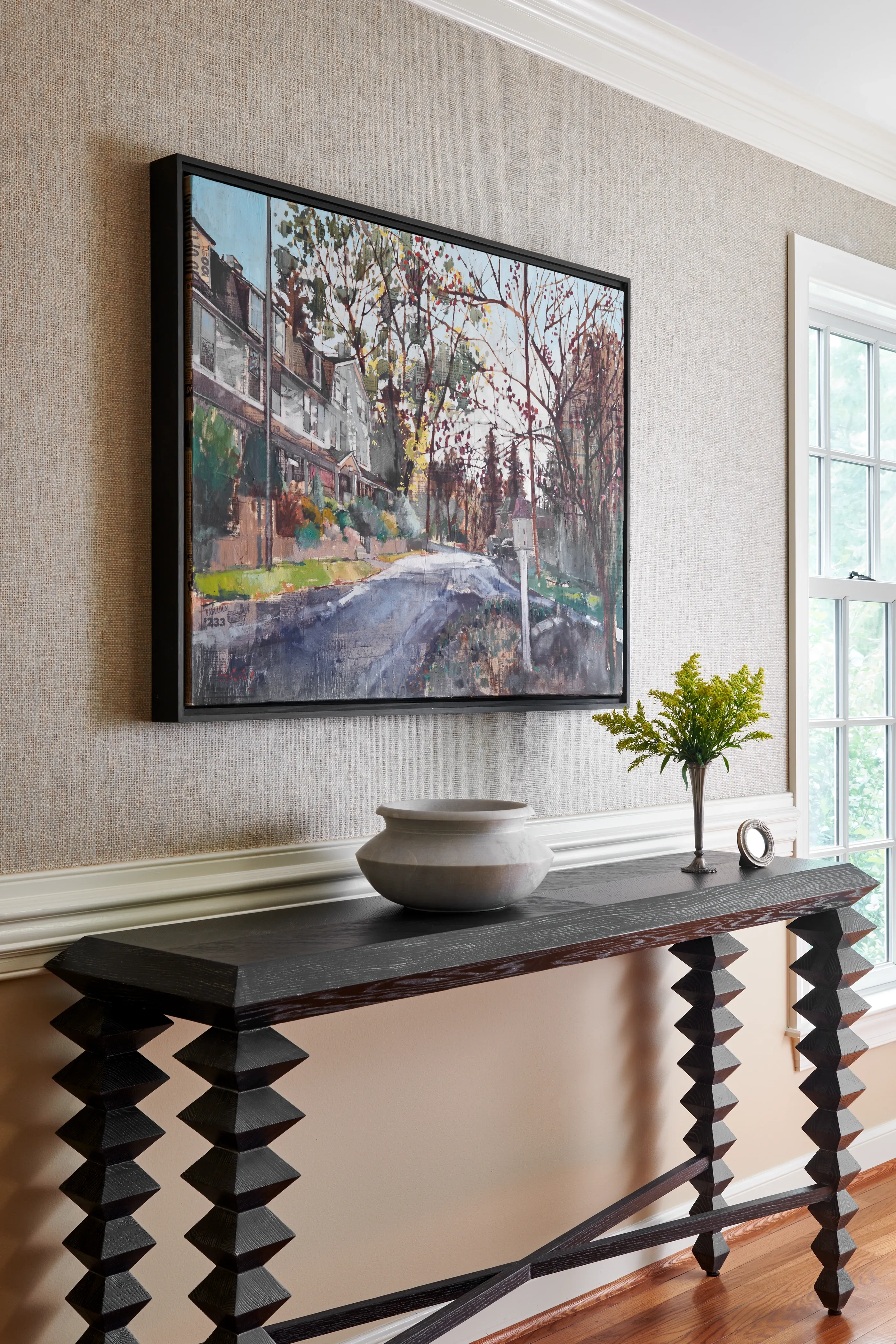Sculptural zigzag-leg console with landscape painting and grasscloth wallcovering