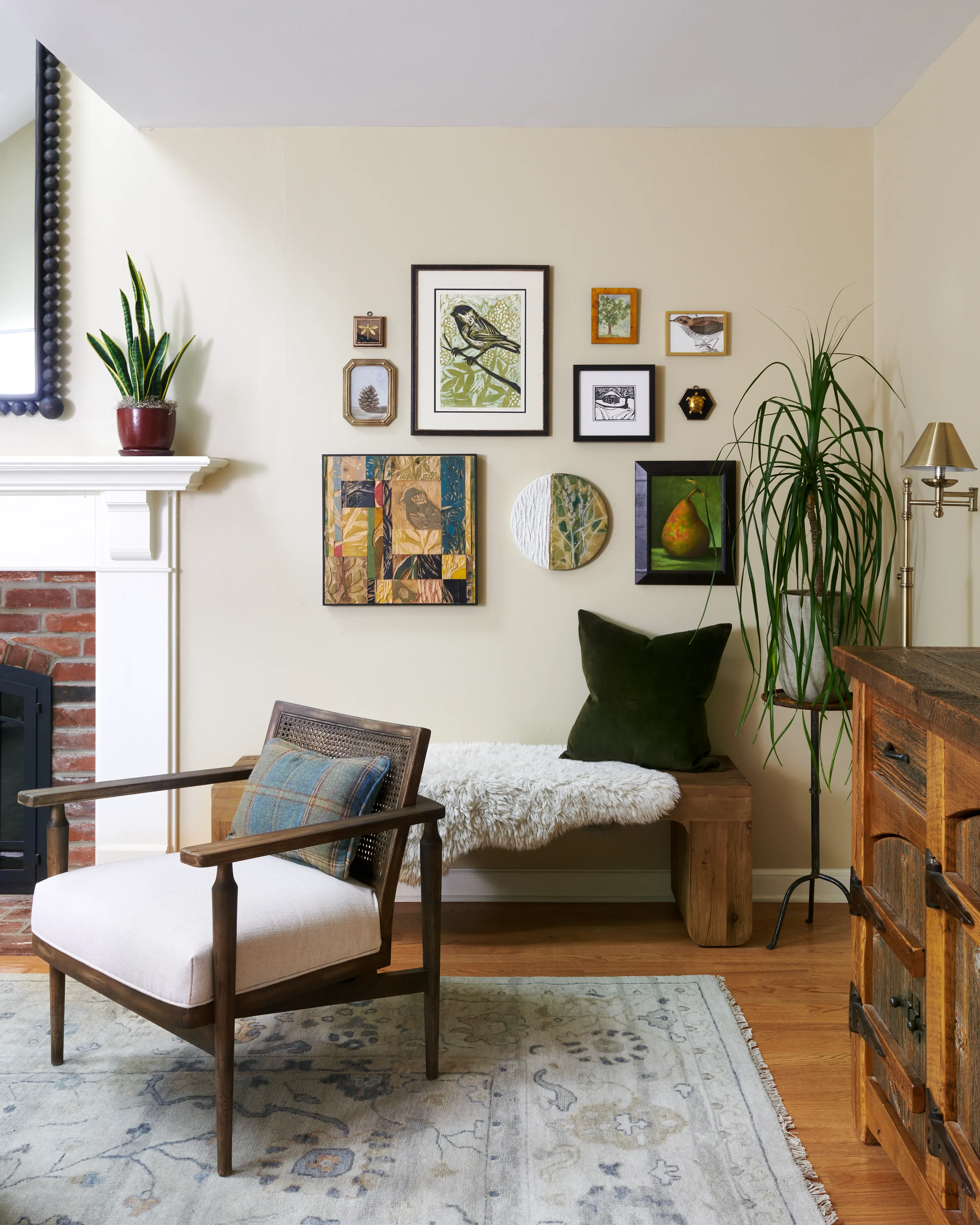 Reading corner with mid-century lounge chair, sheepskin bench, and nature-themed gallery wall
