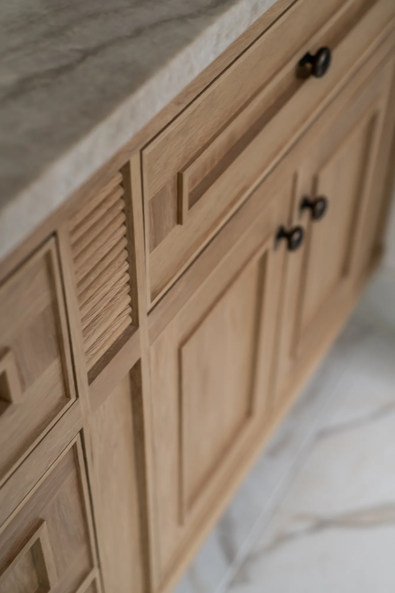 Natural oak louvered cabinetry with black knobs detail