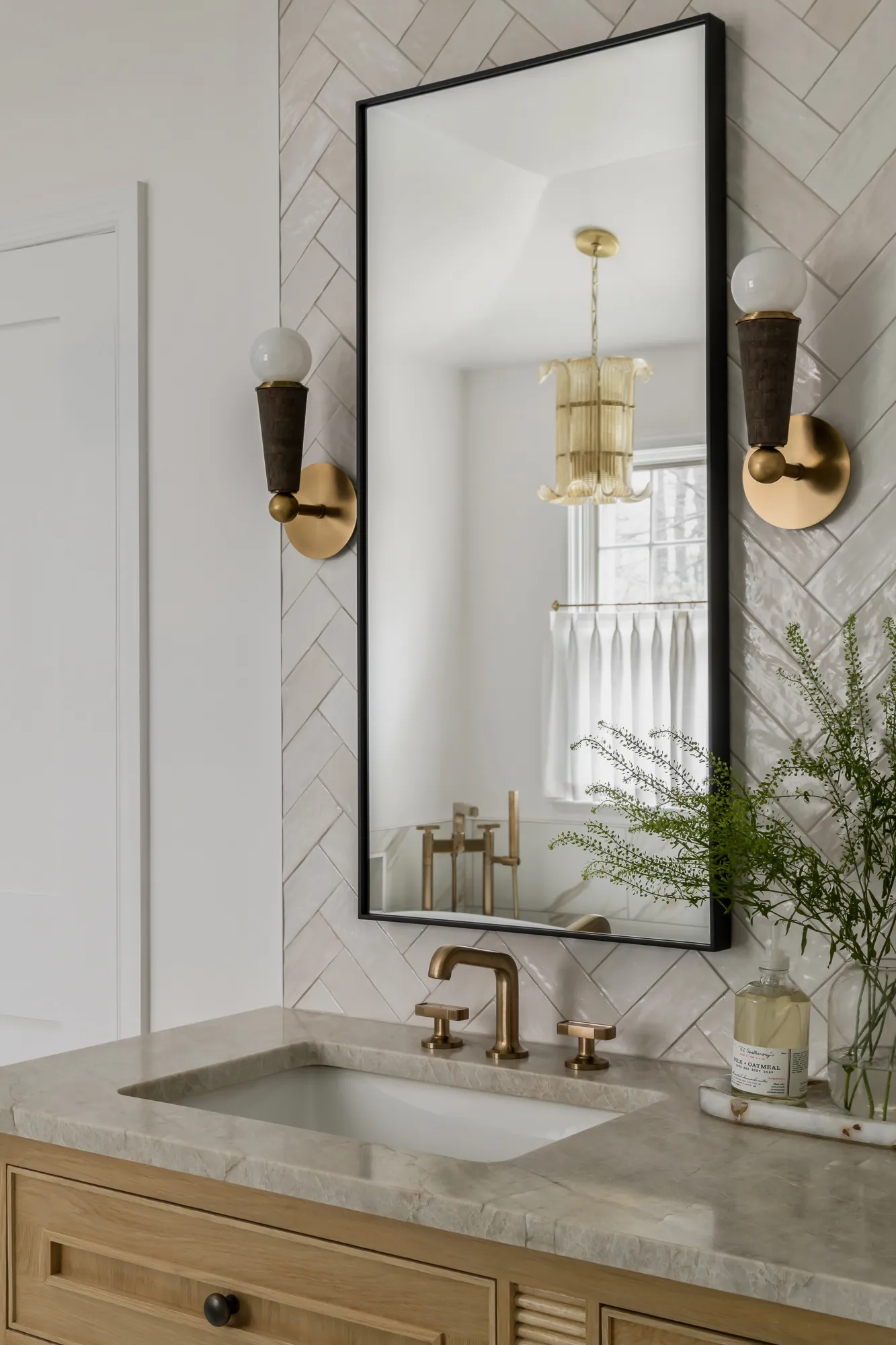 Vanity mirror reflecting tub area and gold pendant