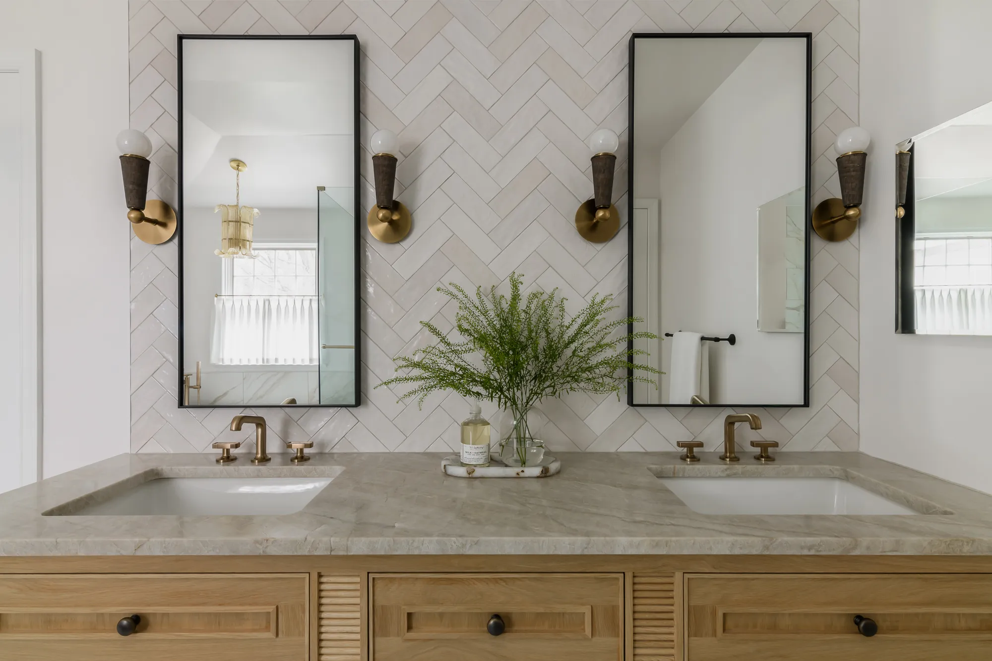 Double vanity front view with herringbone tile and brass sconces